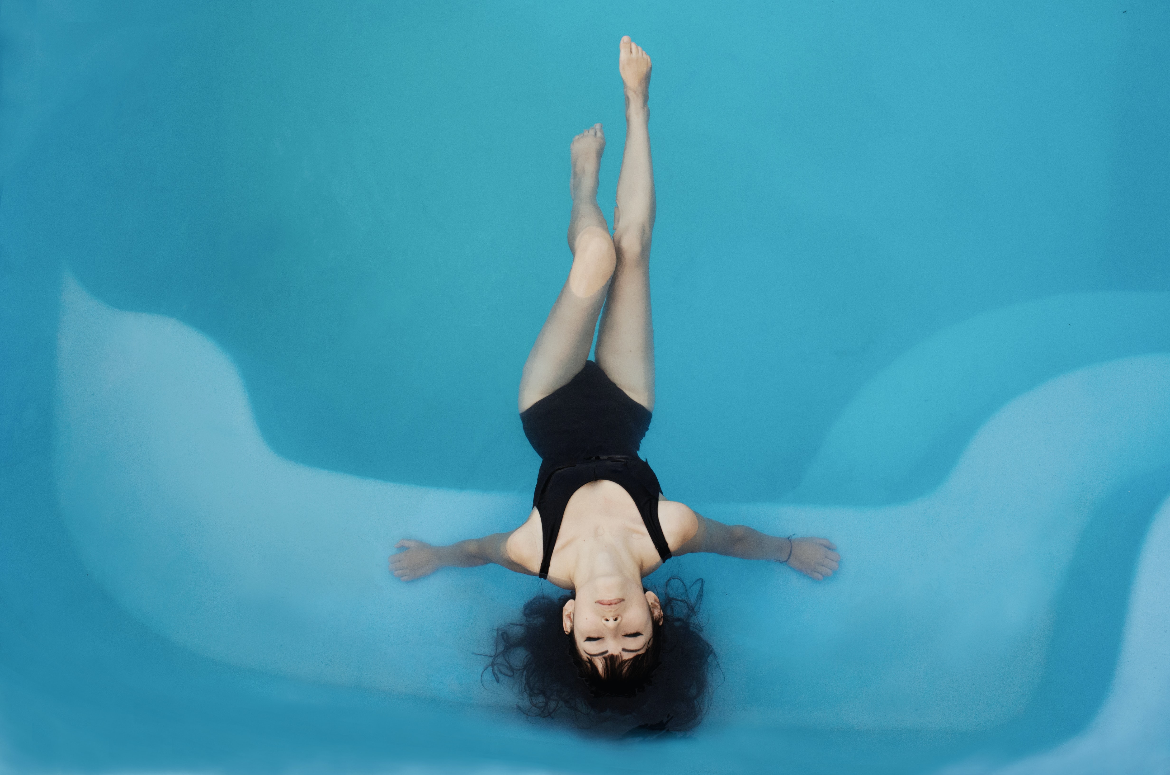 Лоскутова релакс. Девушка лежит в воде. Девушка в бассейне вид сверху. Флоатинг. Девушка ныряет.