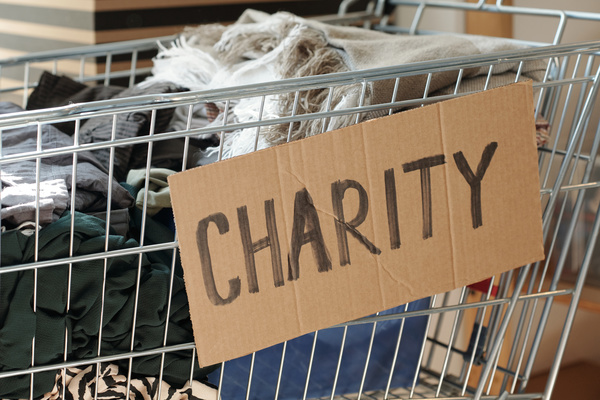 Inscription charity is on the cardboard sign which is on a cart with piles of clothes