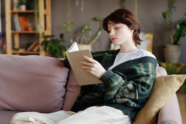 A Girl Reads Sitting on a Sofa