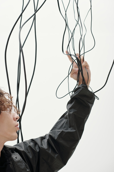A Man Reaches out His Hand and Touches the Wires That Come from the Sleeve of His Jacket