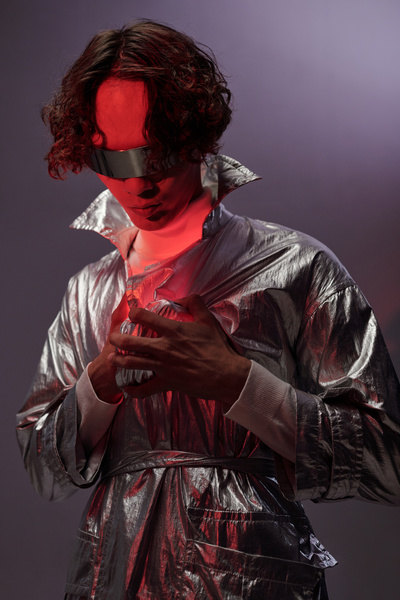 A cyberpunk man lowering his head touches a red luminous heart that illuminates his face