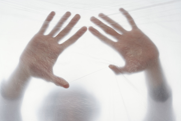 Hands press on the cellophane covering against light background