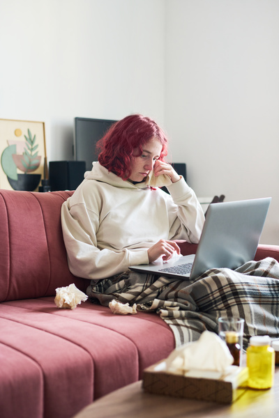A Woman Has a Cold and Is Sitting with a Laptop