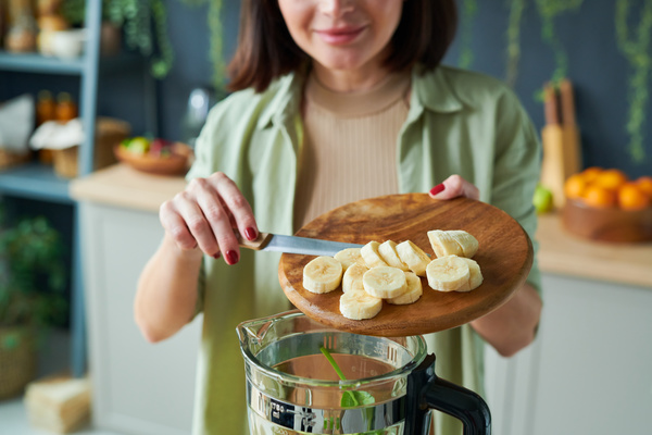 A Woman While Making a Smoothie Pours Banana into a Blender