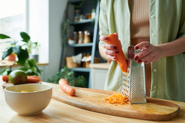 A Woman Grates Carrot on a Board