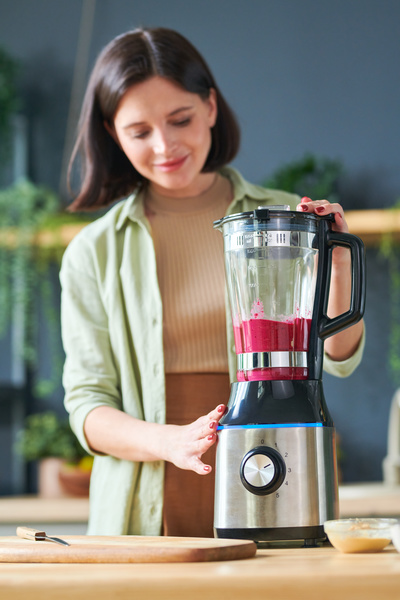 A Woman Grinds Fruits and Berries in a Blender