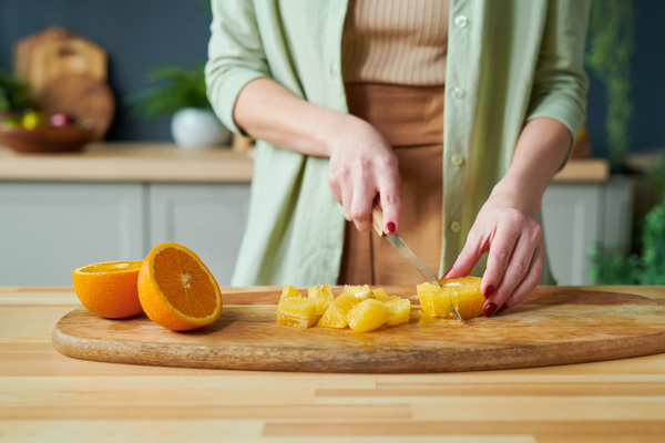 A Woman Making a Smoothie Slices an Orange