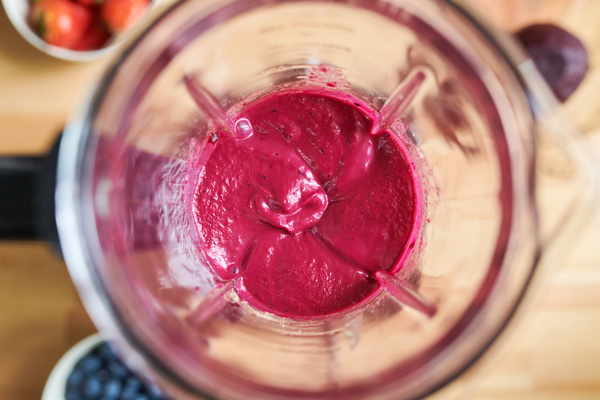 Freshly prepared berry smoothie of bright pink color in a jug of a blender