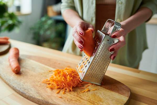 A Smoothie Maker Shred a Carrot on a Grater