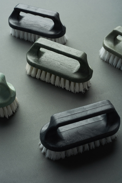 Household iron brushes with dark handles with white bristles are laid out on a black background