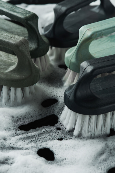 Close-up cleaning iron brushes with handles of dark green shades and white bristles in soap foam