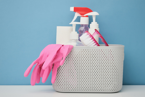 Cleaning chemicals with pink rubber gloves and a scrubbing iron brush in a white plastic basket