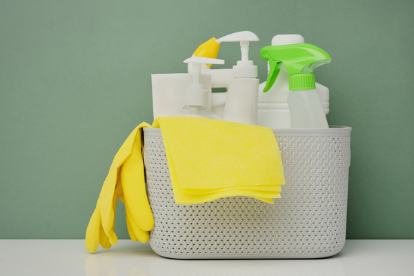 Detergents with yellow rubber gloves and a yellow cleaning cloth in a white plastic basket