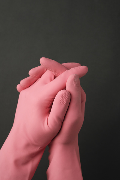 Clasped hands in pink rubber gloves on a dark background