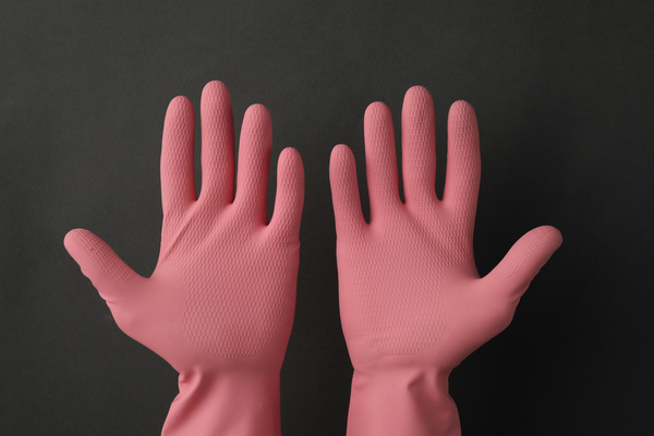Open palms in pink rubber gloves on a dark background