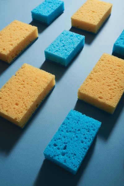 Blue and yellow cleaning sponges neatly arranged in several rows on a blue surface