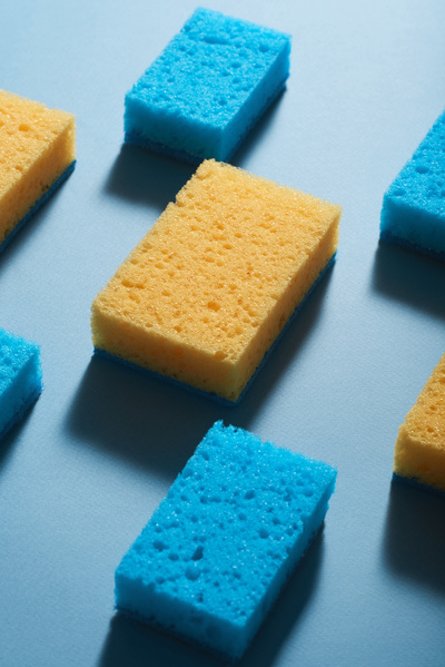 Blue and yellow scrubbing sponges neatly laid out in a checkerboard pattern on a blue surface