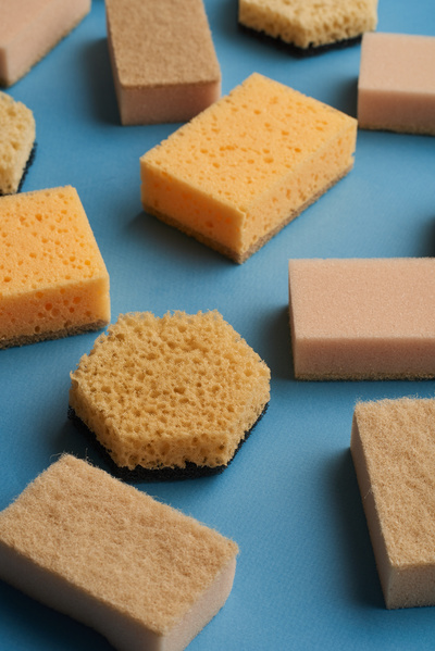 Yellow and beige sponges for washing are randomly laid out on a blue surface