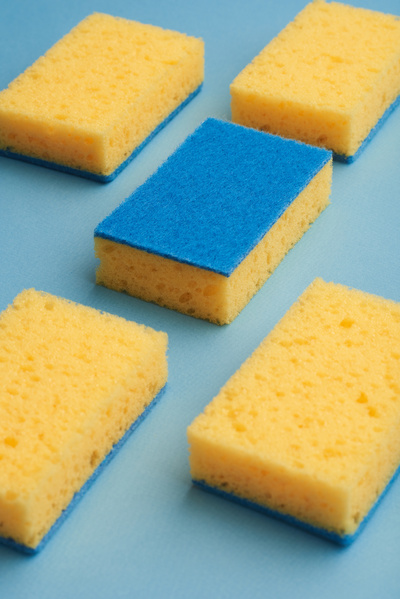 Blue and yellow sponges for washing dishes are laid out on a blue surface
