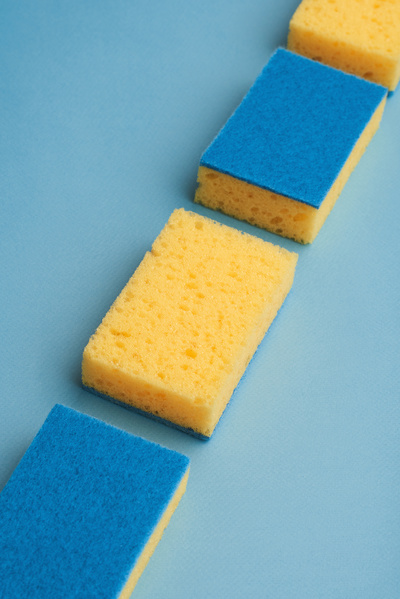 Blue and yellow sponges for washing dishes are laid out in a row on a blue surface