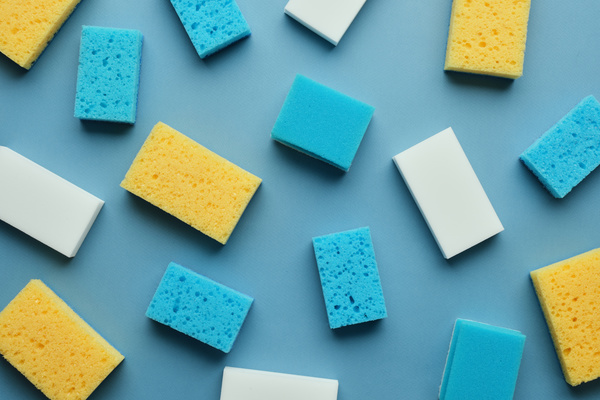 Blue and yellow sponges for washing dishes and melamine sponges lie forming a frame
