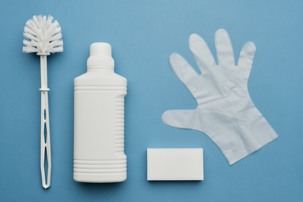 Toilet brush white bottle with detergent melamine sponge and rubber gloves on a blue background