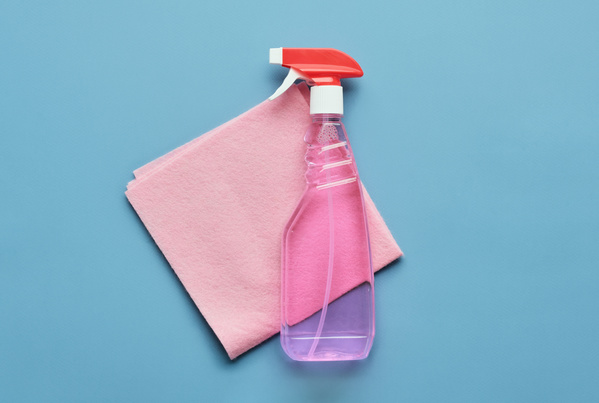 A window cleaning kit consisting of detergent in a spray bottle and a pink viscose napkin on a blue background