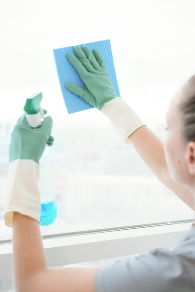 The window is cleaned in rubber gloves with a blue sponge cleaning cloth with a cleaning agent