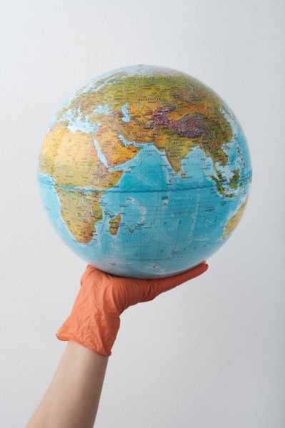 Globe on the palm in a rubber glove of red color on a white background