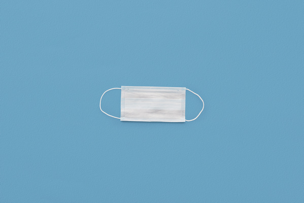 White disposable medical mask on a blue surface