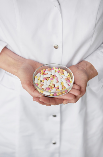 A glass round petri dish with different medicine in the hands of a doctor in a white coat