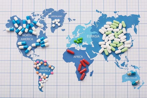 Medicines of various dosage forms and colors are laid out on the continents on the world map