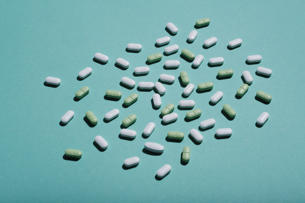 Oval Pills of white and green colors are scattered on a blue surface
