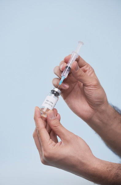 The medicine from the tilted ampule is injected into a small volume syringe with hands