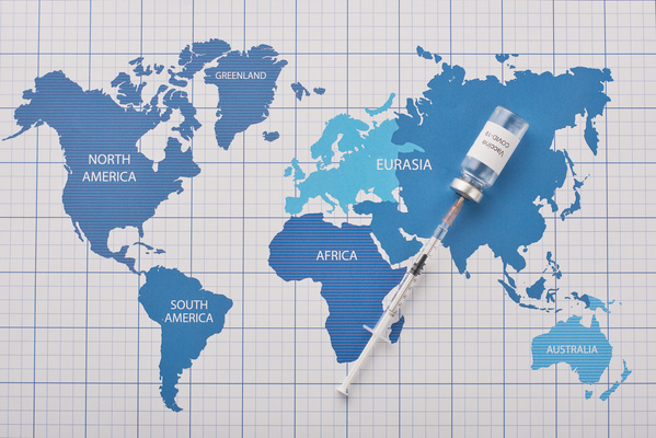 An ampoule with a vaccine pierced with a small volume syringe on a blue world map