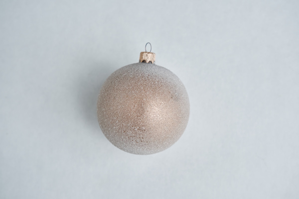 A Christmas bauble decorated with white flakes imitating frost on a red corrugated surface