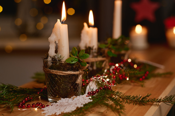 A Christmas composition of lighted candles beads and Christmas tree twigs on a wooden table