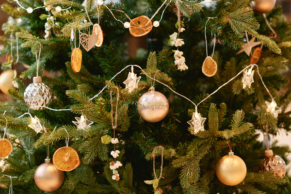 A Christmas tree lavishly decorated with golden and white baubles garlands and wooden and edible decorations