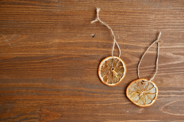 Edible citrus decorations for a Christmas tree on loops of twine lie on a wooden table