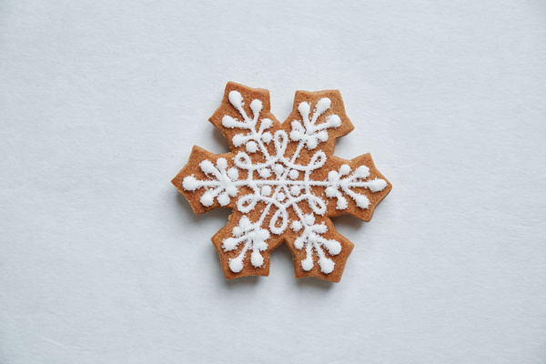 Gingerbread snowflake decorated with a cream pattern on a white surface