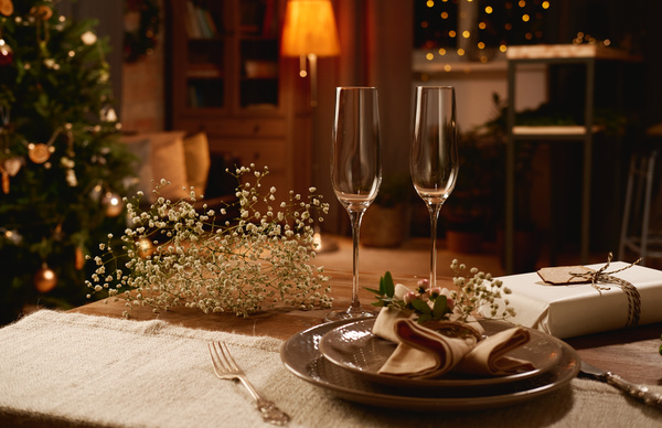 Champagne glasses are on a canned table decorated with gypsophiles in a cozy room with soft light and a Christmas spirit