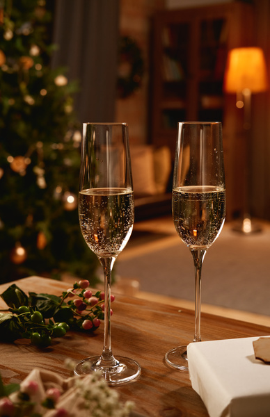 Champagne glasses on a table with flowers in a cozy room with dim lights and a Christmas romantic atmosphere