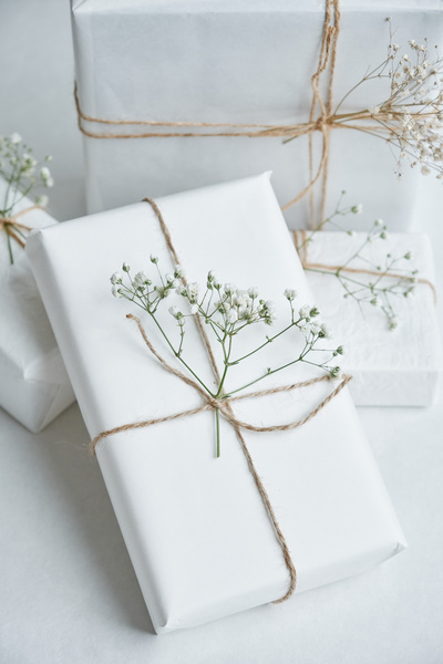 Present boxes packed with white paper and decorated with twine and gypsophiles on a white background
