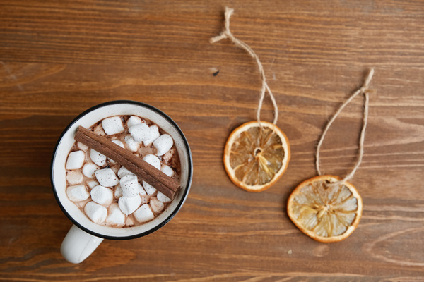Cocoa with cinnamon and marshmallows in a white mug with a black border on the table with edible Christmas decorations