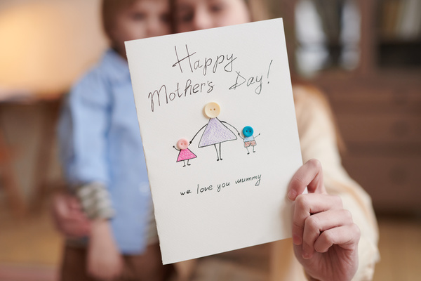 A mothers Day card with a bright pattern and button applique in the hand of a girl with her brother