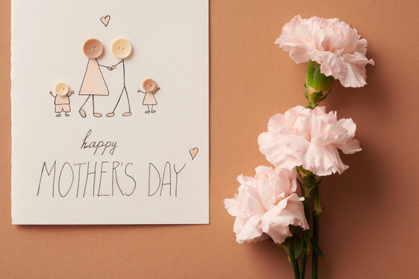 A postcard with a family applique pattern dedicated to Mothers Day with a pink carnation on a light brown background