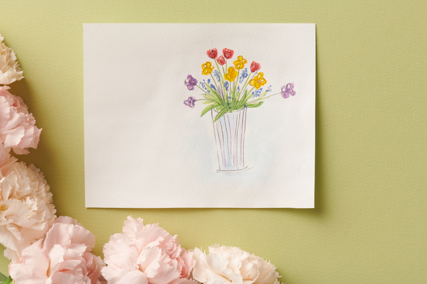 A drawing for Mothers Day of a vase with flowers lying on a bright green background framed by buds of white carnations
