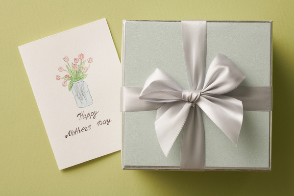 Handmade postcard for Mothers day with an illustration with tulips and a gift box with a silver bow on a bright green background