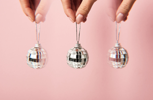 Photo of a duplicating Christmas tree ball in the form of a disco ball which holds a silver thread on a pink background