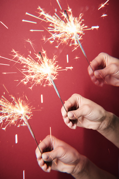 A repeating image of a sparkler shining brightly in the hand on a fuchsia background
